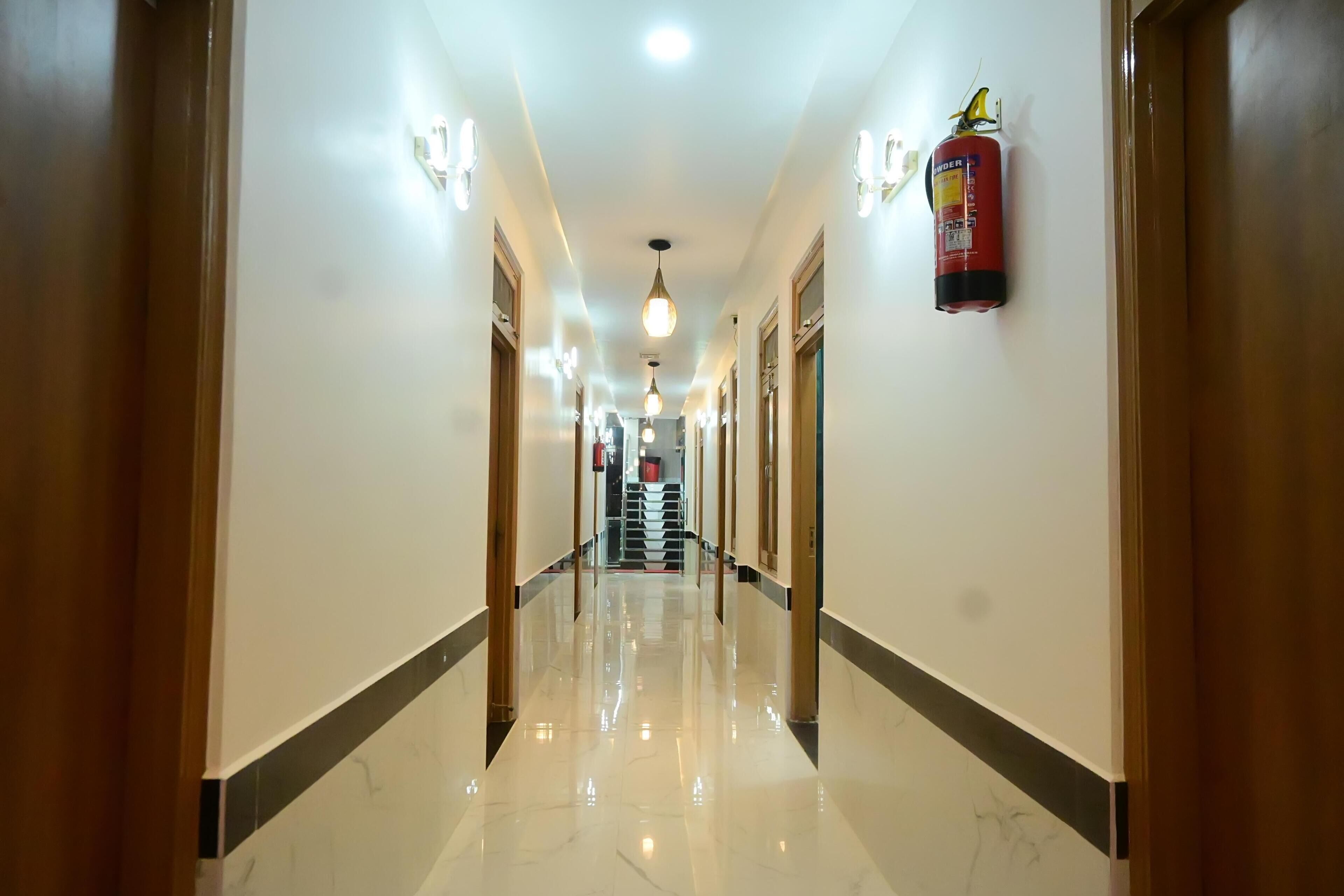 A hotel hallway with a polished marble floor, wooden doors, and pendant lighting.