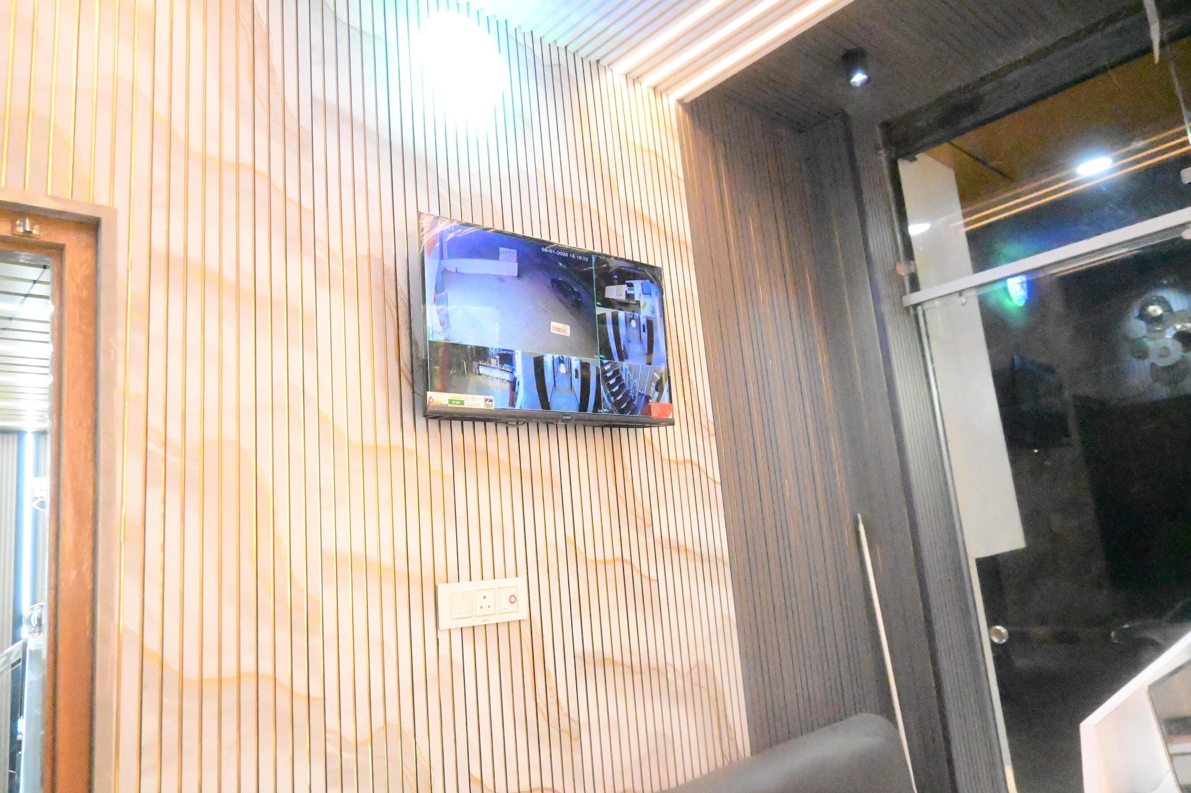 Un televisor montado en la pared en una habitación con un papel tapiz decorativo y una puerta a la derecha.