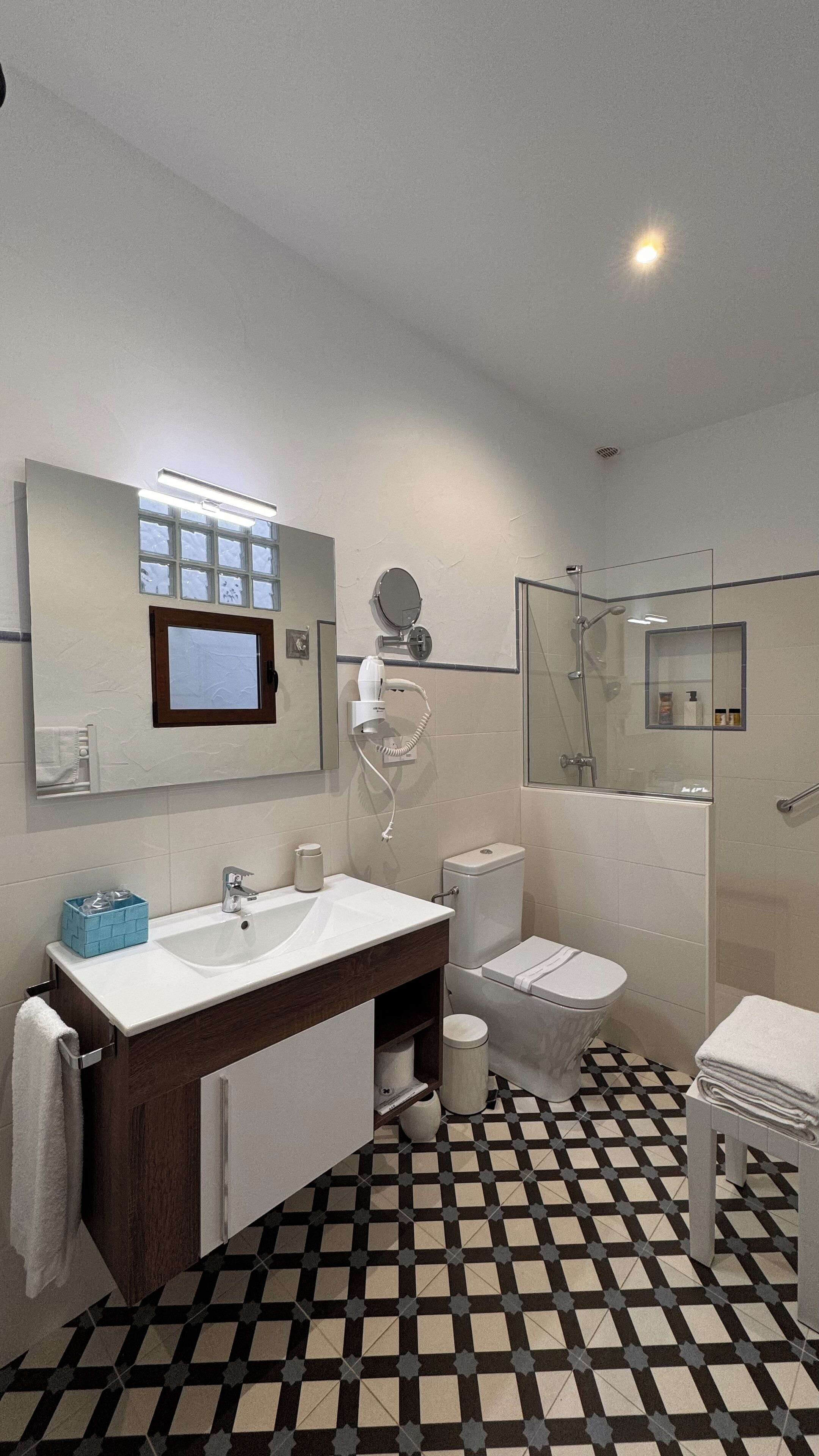 Un baño moderno con un espejo grande, un lavabo, un inodoro y una zona de ducha.