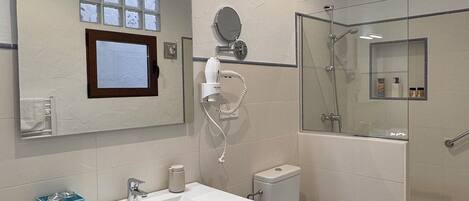 Un baño moderno con un espejo grande, un lavabo, un inodoro y una zona de ducha.