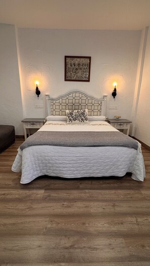 A neatly made bed with a white headboard, two bedside tables with lamps, and a framed picture on the wall.