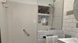 Een moderne badkamer met een douche, een wastafel en een spiegel.