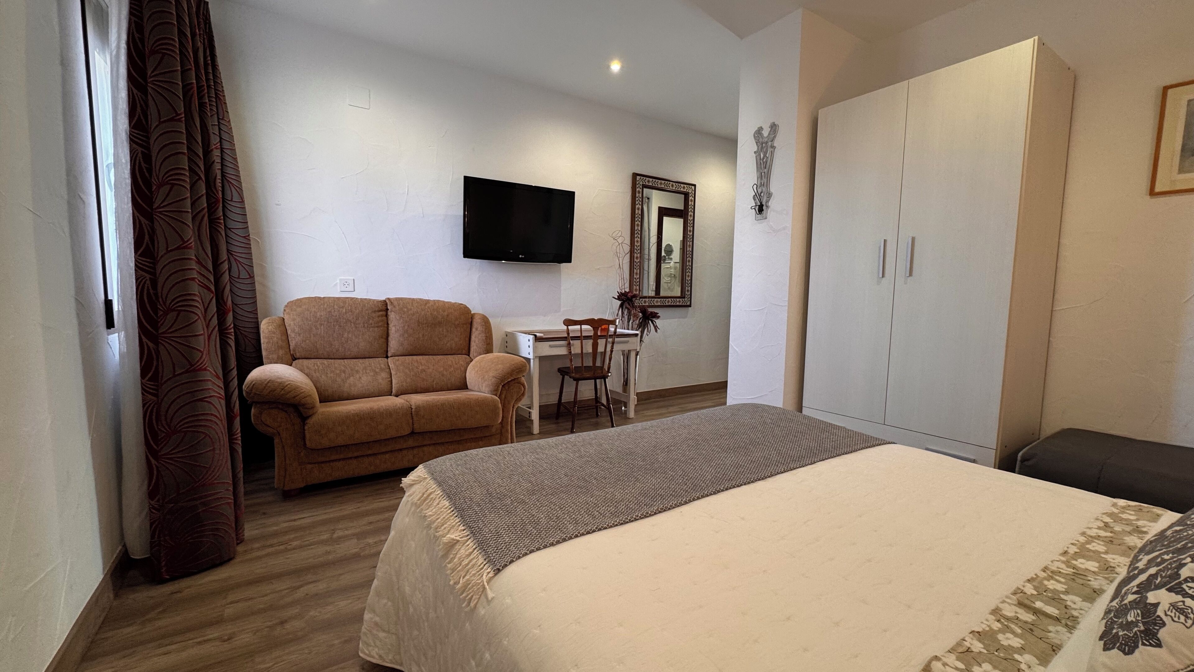 Habitació d'hotel amb llit, sofà, escriptori i armari.