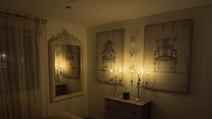 Un dormitorio tenuemente iluminado con cama, cómoda y obras de arte en la pared.