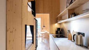 Une cuisine moderne avec des meubles en bois, une cuisinière encastrée et un coin repas comprenant une table et des chaises.
