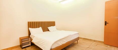 A neatly arranged bedroom with a bed, bedside table, and a door.