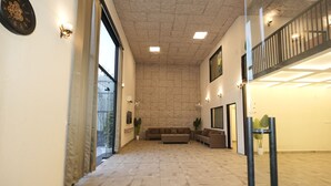 A spacious interior with a stone wall, a sofa, a coffee table, and a staircase. - Dornix by Housiify (Gurugram)