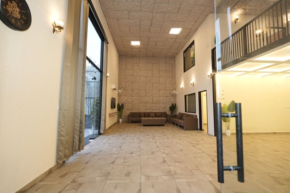 Un intérieur spacieux avec un mur en pierre, un canapé, une table basse et un escalier.