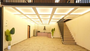 A spacious hallway with a tiled floor, a staircase on the right, and a kitchen area in the background. - Dornix by Housiify (Gurugram)
