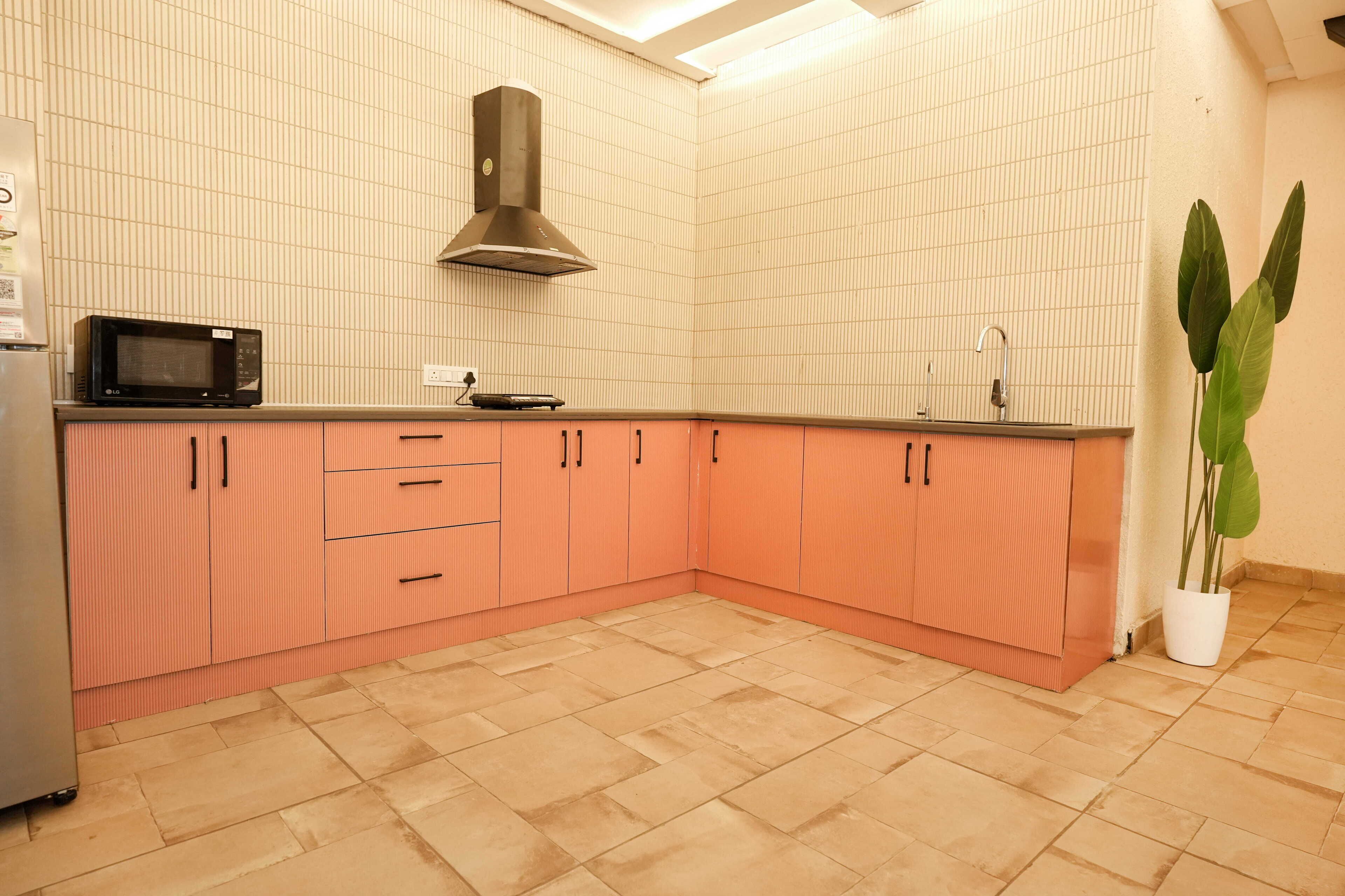 A kitchen with pink cabinets, a microwave, a stove, and a sink.