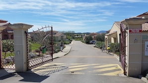 Un cancello conduce a una zona residenziale con case su entrambi i lati.