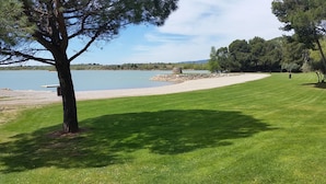 Un'area erbosa con una struttura in pietra vicino all'acqua, circondata da alberi.
