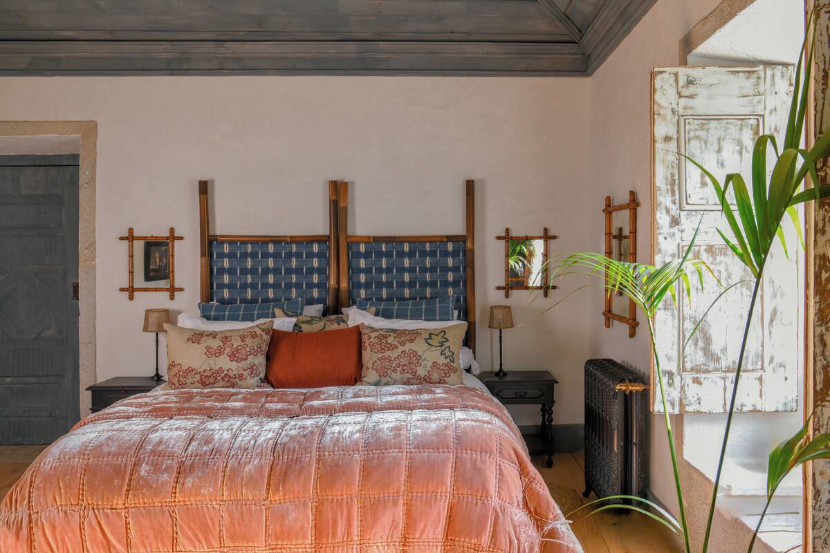 A bedroom with a large bed, wooden headboard, and a nightstand with a lamp.