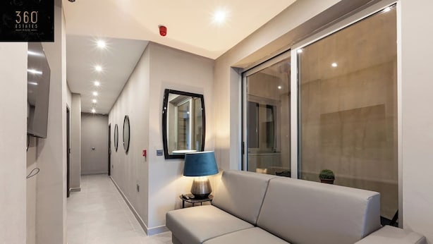 A modern hotel corridor with a sofa, a lamp, and a large mirror. - A lovely vacation 5BR/5BATH home with WIFI & AC (L-Imsida)