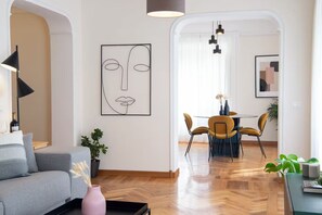 Un salon moderne avec un canapé, un coin repas comprenant une table et des chaises, et un grand tableau abstrait accroché au mur.