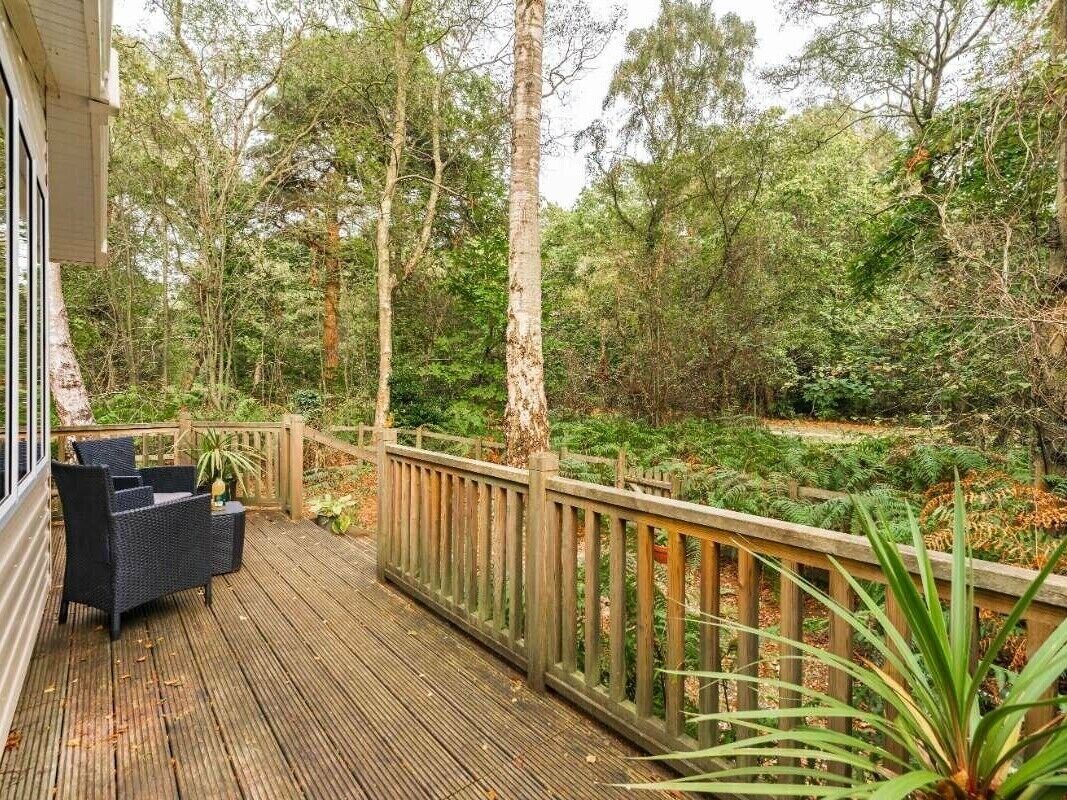 A wooden deck with outdoor furniture, surrounded by dense forest.