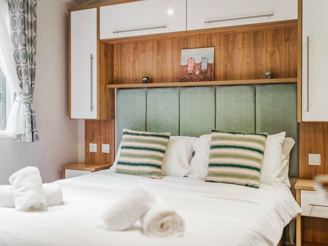 A hotel room with a bed, wooden headboard, and a painting above it.