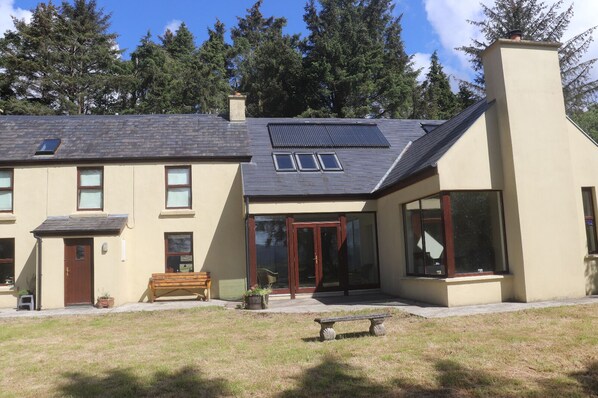 A two-story house with a sloped roof, large windows, and a chimney.