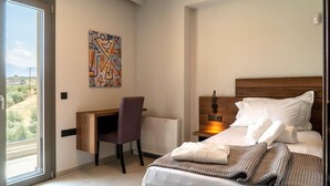 A modern hotel room with a bed, a desk, and a chair. - Anthemis Luxury Villas 2 (Heraklion)