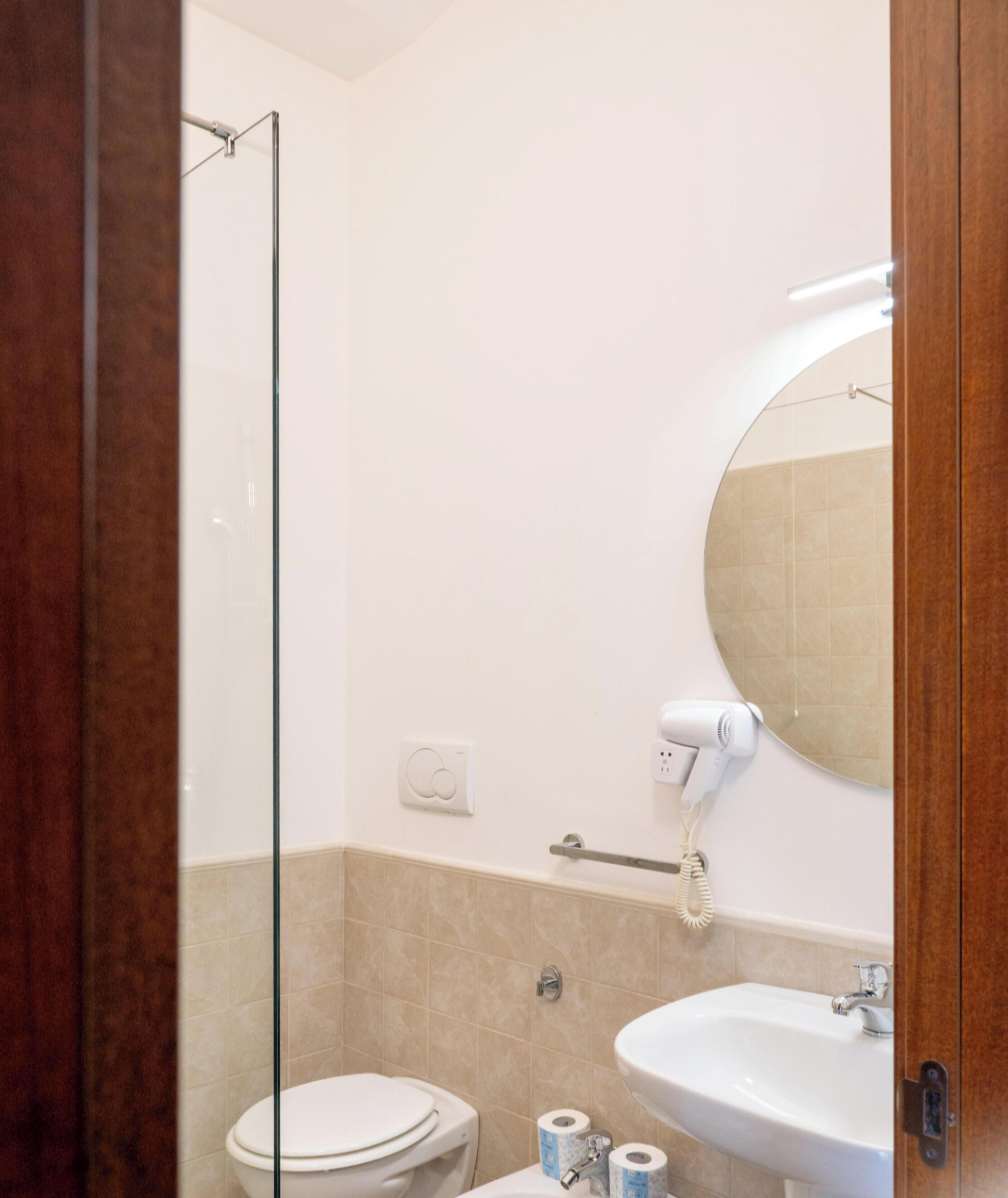 A bathroom with a toilet, sink, and a hairdryer mounted on the wall.