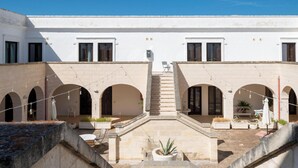A courtyard with arches, a central staircase, and outdoor seating.