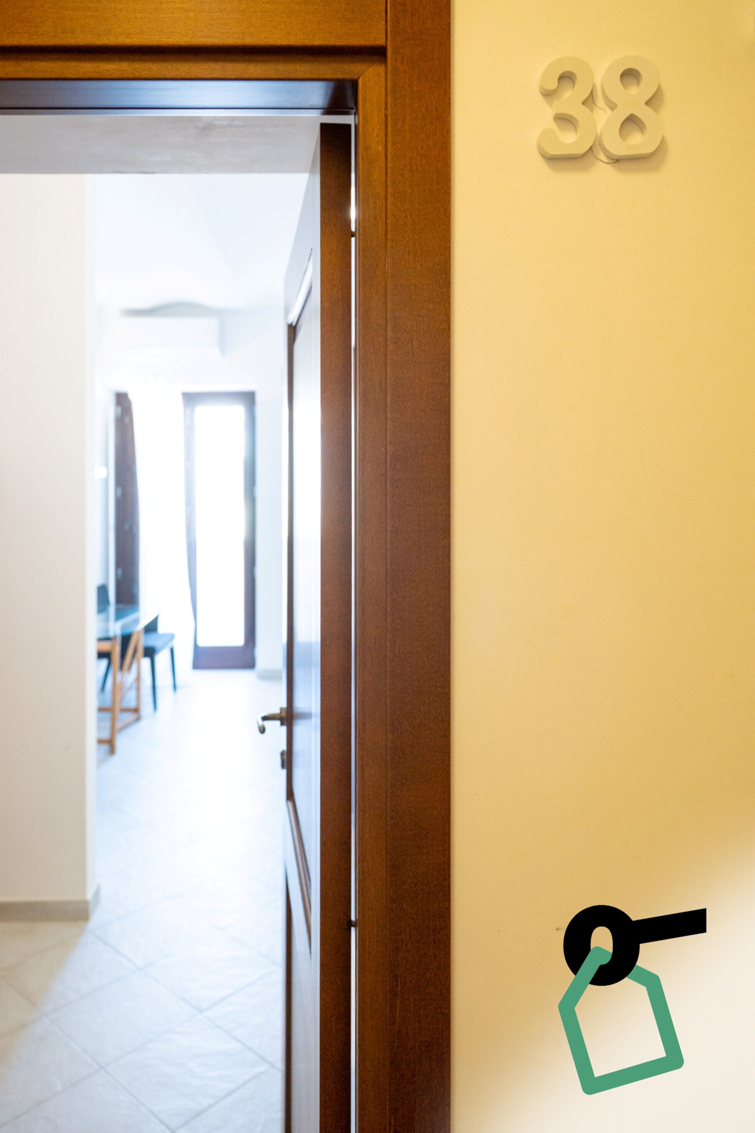 Une porte portant le numéro « 38 » et munie d’un trou de serrure, qui donne sur une pièce contenant une chaise et une table.