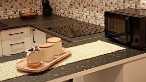Una cucina moderna con forno a microonde, macchina del caffè e tagliere in legno sul piano di lavoro.