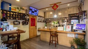 A restaurant interior with wooden furniture, a TV screen, and a variety of dishes displayed on shelves. - Templeside Courtyard Hotel  (Beijing)