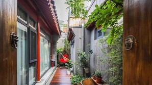 A narrow alleyway with wooden doors, a hanging chair, and potted plants. - Templeside Courtyard Hotel  (Beijing)