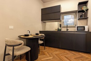 A compact kitchen with a central island, two chairs, a microwave, and a window with a view.