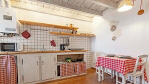 Una cucina con mobili in legno, un forno a microonde, un lavandino e un'area pranzo con tavolo e sedie.