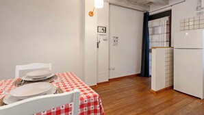 Una stanza con un tavolo da pranzo apparecchiato per due, un frigorifero bianco e un pavimento in legno.