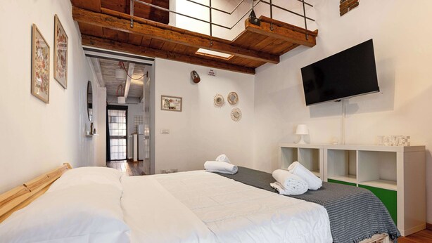 Una camera da letto con un letto, una TV, una scrivania e una mensola.