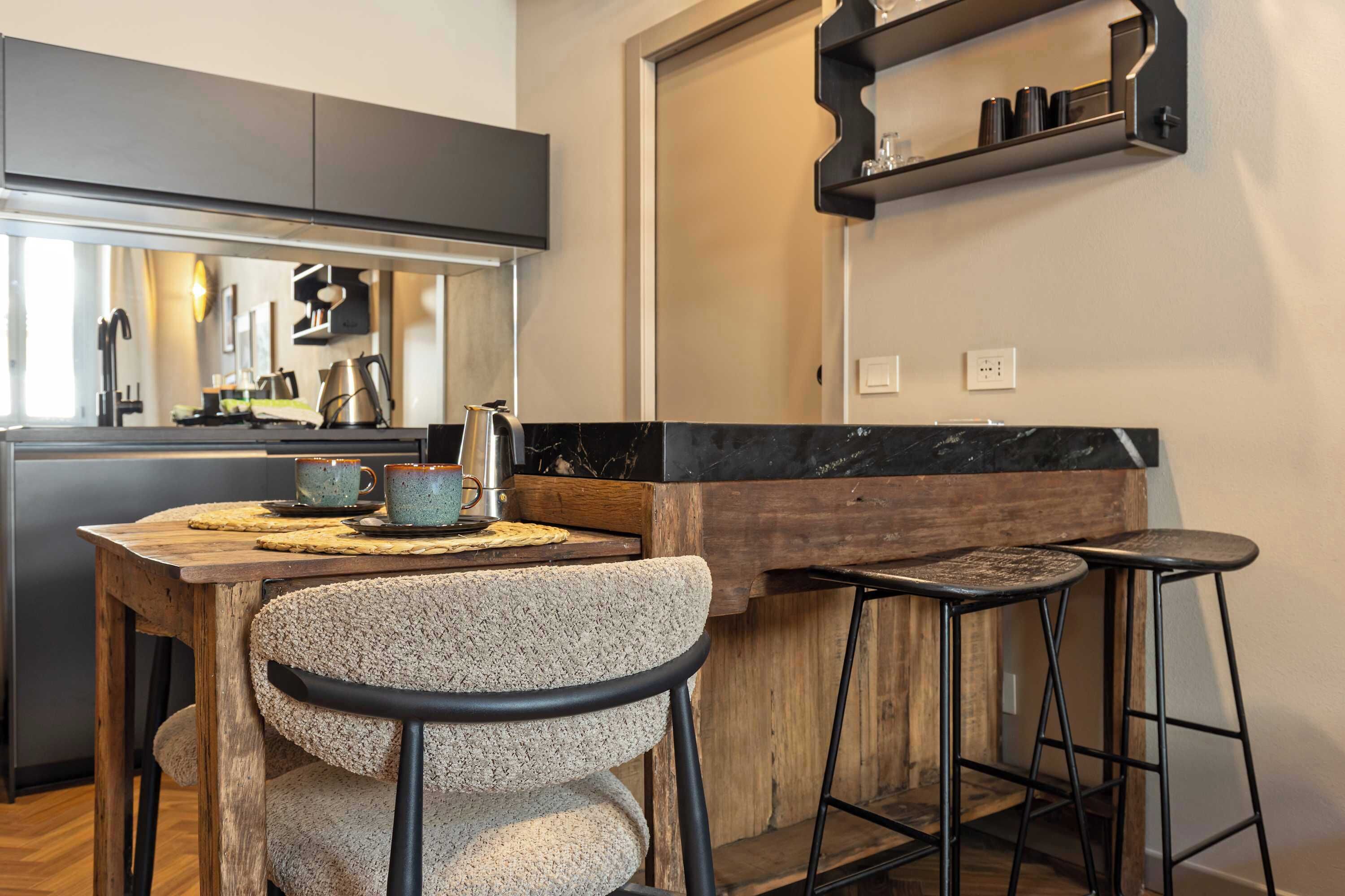 Una cocina moderna con una mesa de madera, taburetes de bar y una cafetera.