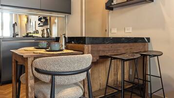 Una cocina moderna con una mesa de madera, taburetes de bar y una cafetera.
