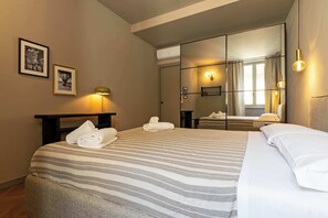 A hotel room with a bed, a mirror, and a nightstand. - Appartamento Smeraldo - Immobili e Soluzioni Rent (Bergamo)