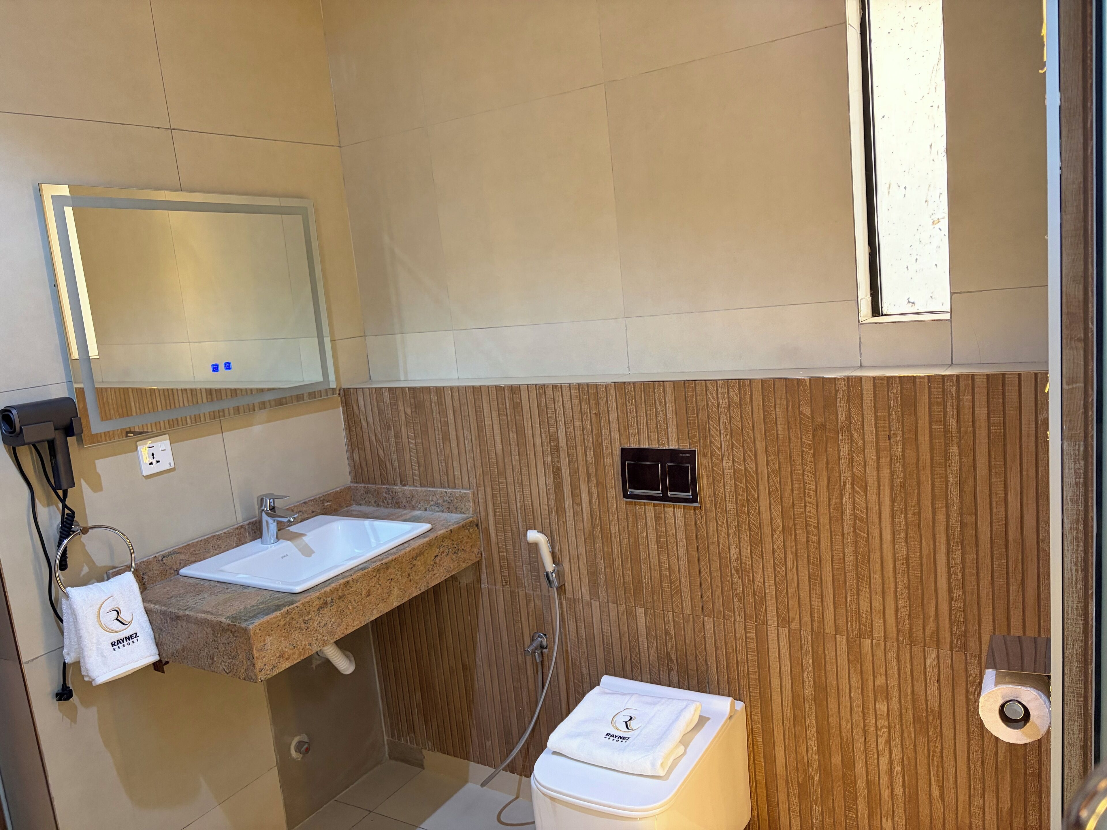 A bathroom with a sink, mirror, towel, and toilet.