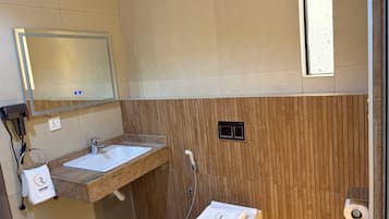 Un baño con lavamanos, espejo, toalla y retrete.
