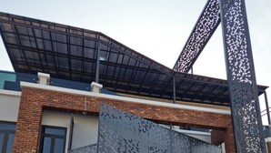 A modern building with a flat roof, a balcony with a patterned metal railing, and a brick facade. - Raynez Resort (Abuja)