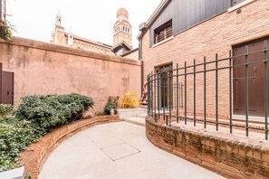 Ein Innenhof mit Ziegelmauer, Metallzaun und einem Gebäude mit dunkler Fassade.
