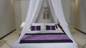 Ein Bett mit Baldachin, zwei Nachttische und eine violette Tagesdecke.