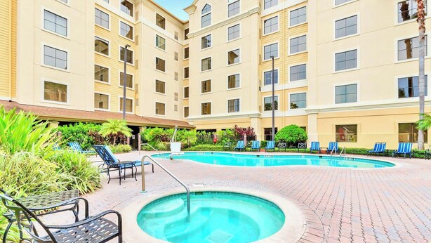 A hotel courtyard with a swimming pool, lounge chairs, and a hot tub. - Studio - Pool Hot Tub Near Universal Studios (Orlando)