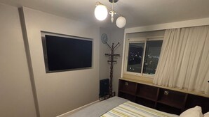 A bedroom with a bed, a window with curtains, a wall clock, and a ceiling light fixture. - Soho 360 Views Flat (London)