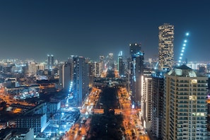 Paisagem urbana noturna com arranha-céus, ruas iluminadas e um ambiente urbano denso.