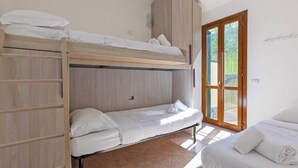 Une chambre avec un lit superposé, une échelle en bois, une armoire et une porte donnant sur un espace extérieur.