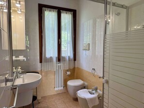 A bathroom with a sink, toilet, bidet, and a window with curtains. - App.3- Le Terrazze del Garda Immobili e Soluzioni (Manerba del Garda)