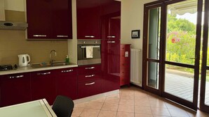 Una cocina con armarios rojos, una estufa, un lavamanos y una ventana con vistas al verdor.