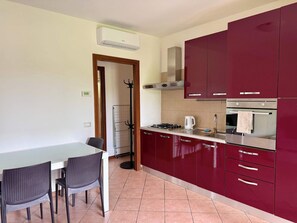 Eine Küche mit Esstisch, Stühlen, Herd, Backofen und Schränken.