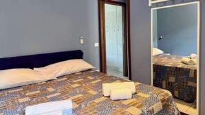 Un dormitorio con cama, aire acondicionado, armario, espejo y perchero.