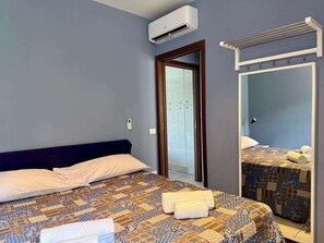 A bedroom with a bed, an air conditioner, a wardrobe, a mirror, and a towel rack. - App.1- Le Terrazze del Garda Immobili e Soluzioni (Manerba del Garda)